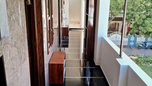 Un pasillo estrecho con un banco de madera, suelo de baldosas y vista a la calle.