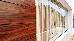 Fachada de un edificio moderno con pared de paneles de madera y un gran ventanal con cortinas traslúcidas.