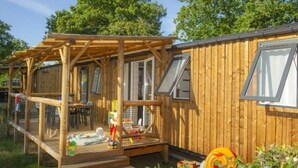 Une cabane en bois avec une terrasse, une cage à oiseaux et une fenêtre.