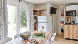 Une cuisine moderne équipée d’un four à micro-ondes, de meubles en bois et d’un coin repas avec une table dressée pour deux personnes.