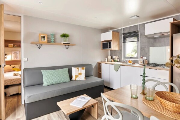 A compact living space with a sofa, a dining table, and a kitchenette.