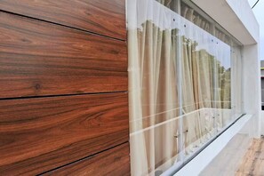 Ein modernes Gebäude mit Holzverkleidung und großen Fenstern mit transparenten Vorhängen.