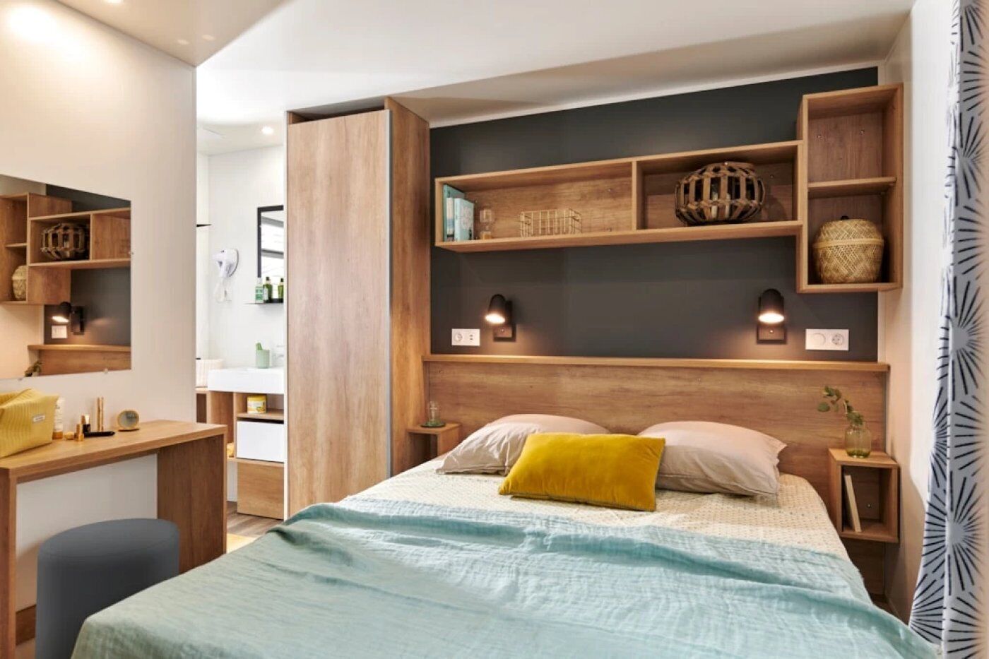 A modern bedroom with a large bed, wooden headboard, bedside tables, and built-in shelves with decorative items.