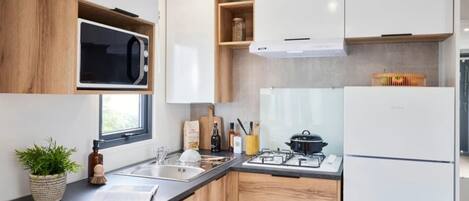 A modern kitchen with wooden cabinets, a built-in microwave, a gas stove, and a refrigerator.