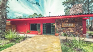 Un bâtiment rouge avec une façade en pierre et une terrasse en bois menant à l’entrée.