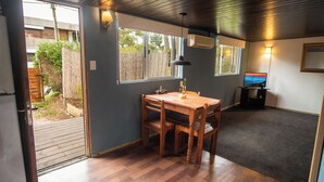 Une cuisine compacte avec une table et des chaises en bois, une fenêtre donnant sur le jardin, et un système de climatisation intégré.
