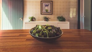 Une table en bois avec un saladier rempli de salade au premier plan.
