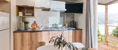 Een moderne keuken met houten kasten, een ingebouwde kookplaat en een eethoek met een tafel gedekt voor twee personen.