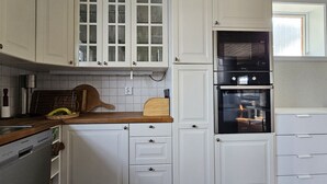 Eine Küche mit weißen Schränken, einem eingebauten Backofen und einem Fenster über der Spüle.