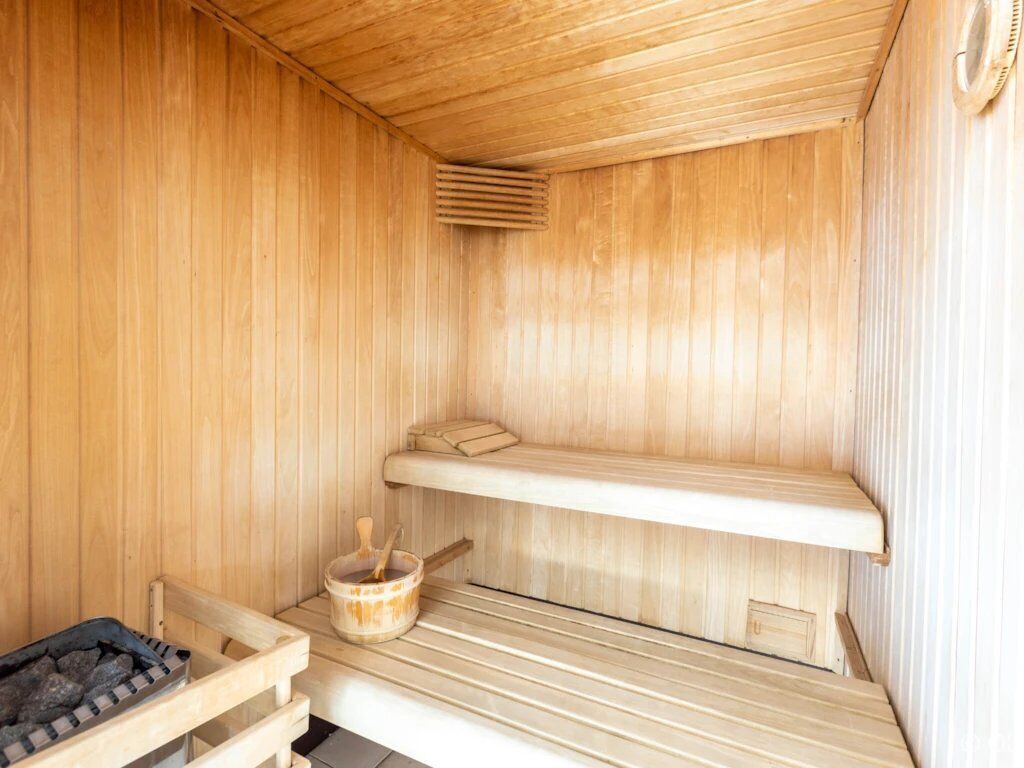 Un sauna en bois avec des bancs et un seau rempli de pierres.