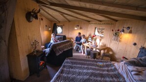 Acogedora habitación tipo cabaña de madera con dos camas, una mesa de comedor y una chimenea.