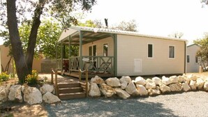 A single-story mobile home with a covered porch and a stone wall.