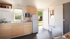 Eine moderne Küche mit Holzschränken, einem Gasherd, einer Mikrowelle und einem Kühlschrank.