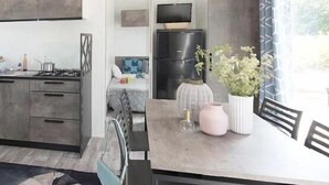 A modern kitchen with a dining area, a built-in TV, and a refrigerator.