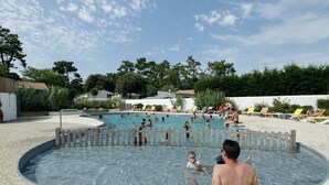 A swimming pool area with multiple pools, surrounded by lounge chairs and a sandy area.
