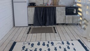 A compact kitchen with a white refrigerator, a sink, and a stove. There is a window overlooking a residential area.