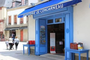 A storefront with a blue awning labeled "BISCUITERIE DE CONCARNEAU" and a display of books and magazines inside.