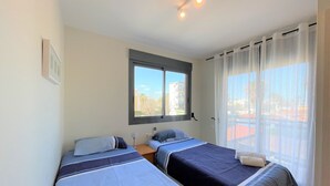 Habitación de hotel con dos camas, una ventana y vistas a edificios.