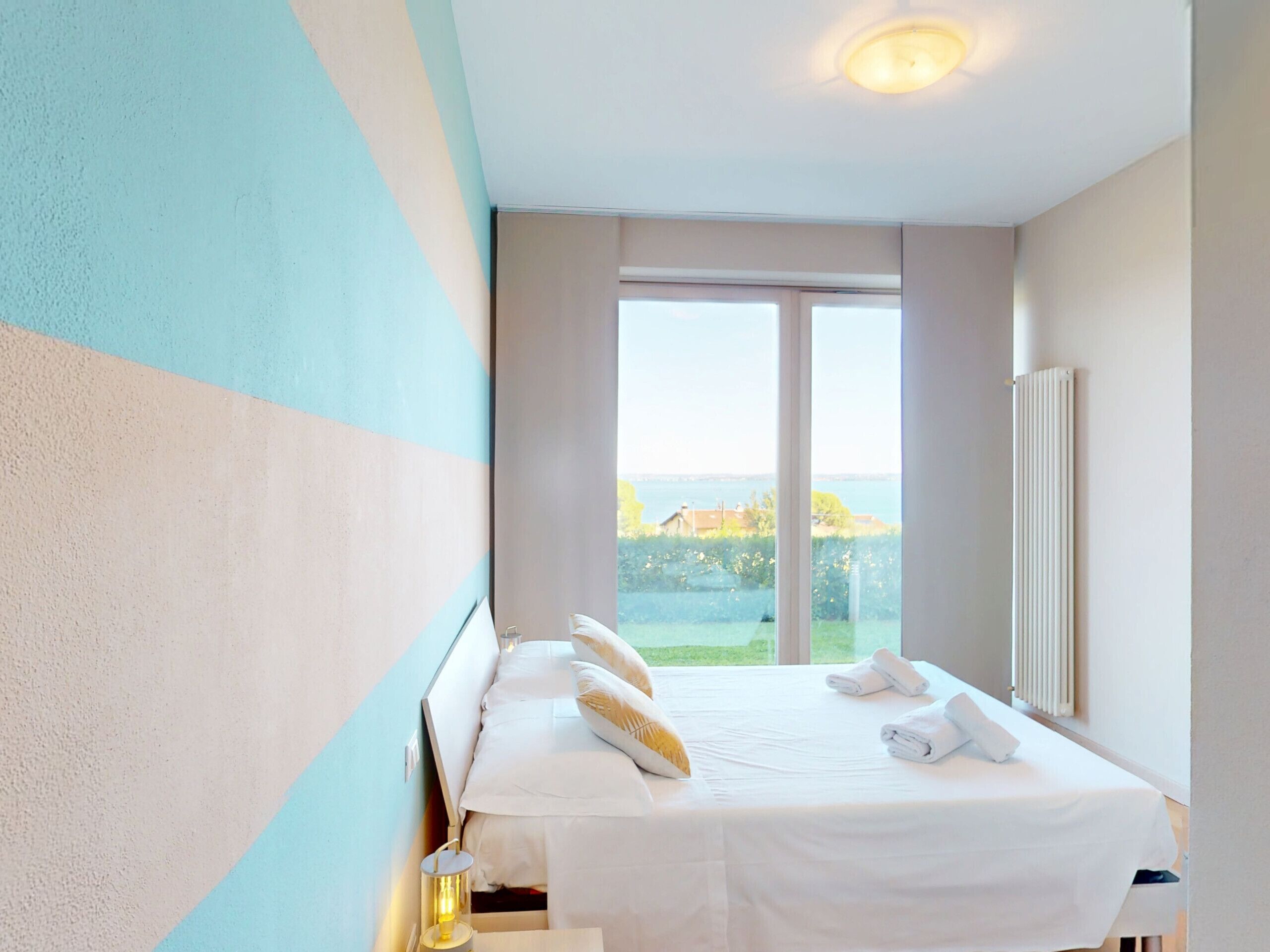 Une chambre d’hôtel avec un grand lit, une vue sur la mer et un radiateur au mur.