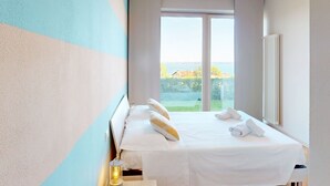A hotel room with a large bed, a view of the sea, and a radiator on the wall. - Horizon luxury lake view by Bookinggardalake (Moniga del Garda)