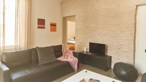 A living room with a stone wall, a sofa, a coffee table, and a television.