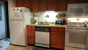 A compact kitchen with a refrigerator, dishwasher, stove, microwave, and a coffee maker.