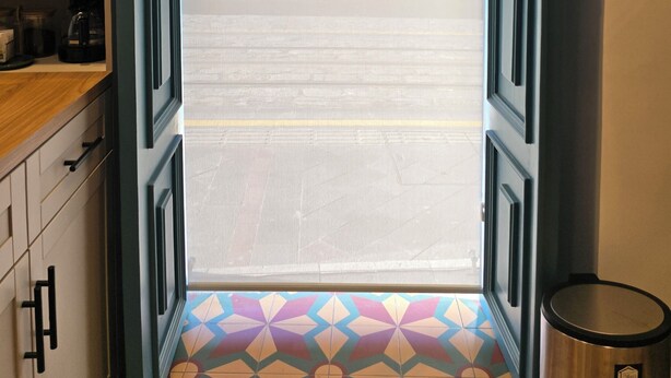 Una entrada que da a una calle con piso de baldosas y un edificio visible al fondo.