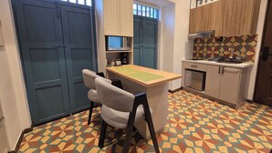 Cocina compacta con comedor, equipada con microondas, cafetera y un refrigerador pequeño.
