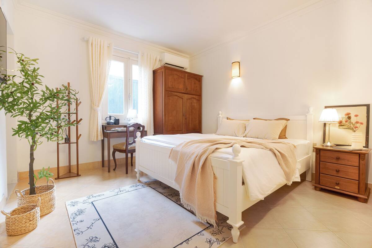 A bedroom with a bed, bedside table, lamp, and a wardrobe.