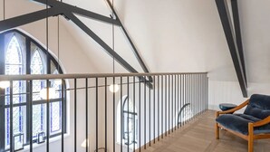 Et moderne interiør med trægulv, gelænder i sort og en blå stol.