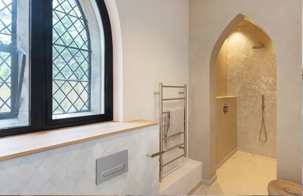 A bathroom with a window, a towel rack, and a shower area.