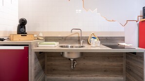 Una cocina moderna con un lavamanos de acero inoxidable, encimera de madera y salpicadero de azulejos.