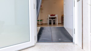Una puerta que da a una habitación con una rampa, una silla blanca y una mesa con un mantel rojo.