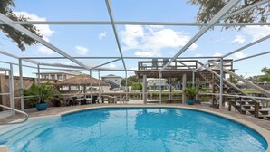 Une piscine avec une terrasse en bois et un abri au toit de chaume.