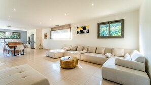 A modern living room with a sectional sofa, a round coffee table, and a dining area with a table and chairs.