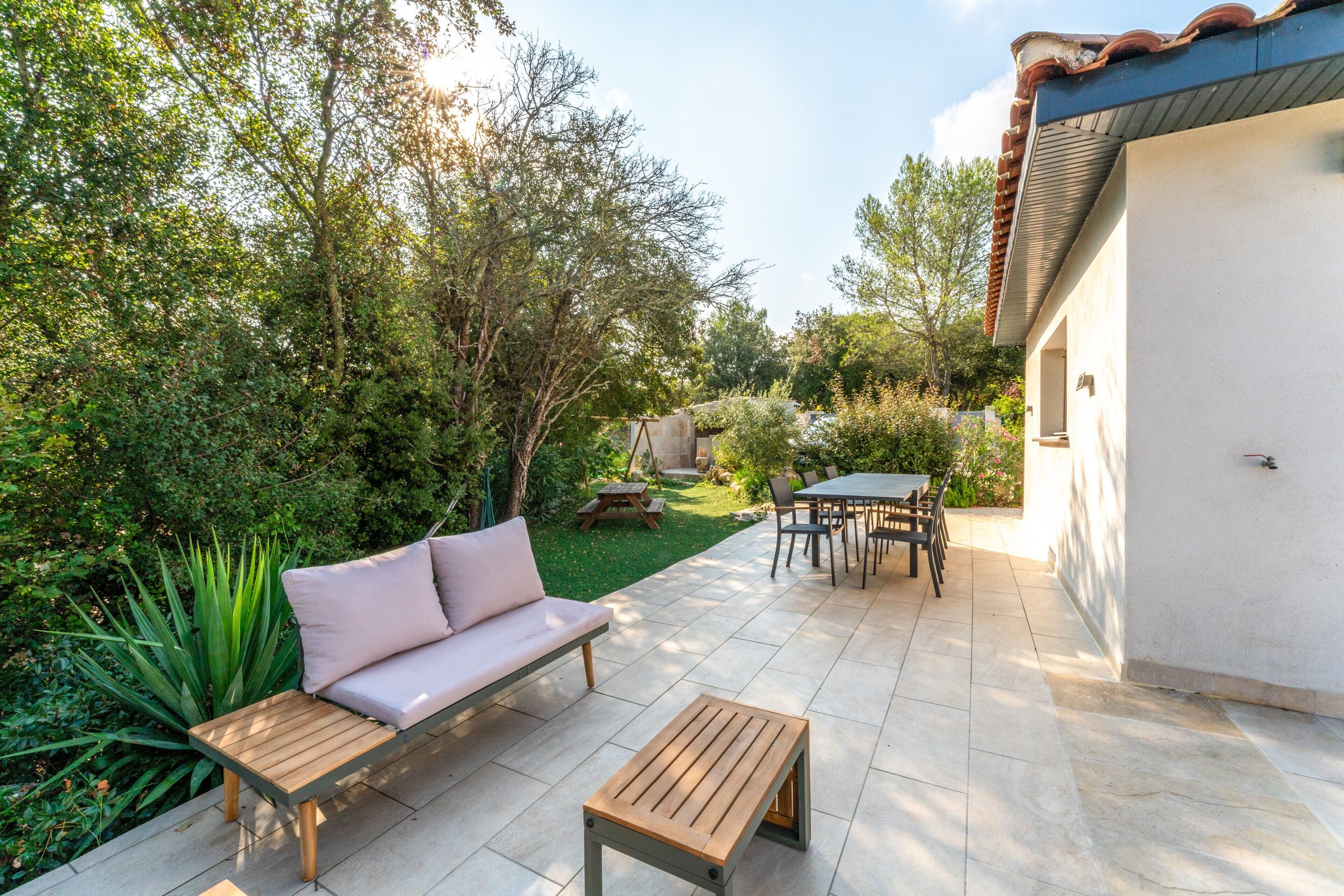 A patio with a sofa, a wooden table, and a dining set.
