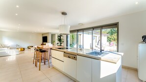 A modern kitchen with a large island, bar stools, and a view to the outside.