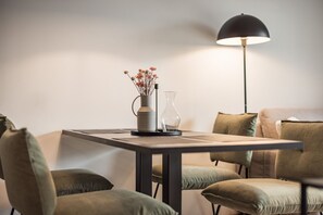 Un espace repas moderne comprenant une table, des chaises, un vase avec des fleurs, une lampe et un luminaire fixé au mur.