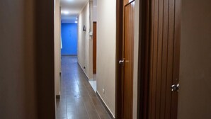 A hallway with wooden doors and a blue wall at the end.