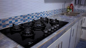 A kitchen with a black stove top, a sink, and tiled backsplash.