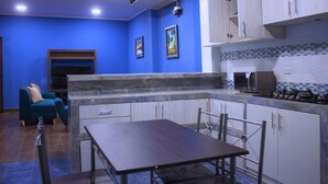 A modern kitchen with a dining area, blue walls, and a built-in microwave.