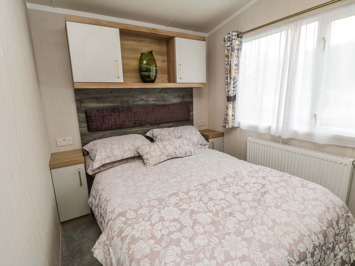 Een slaapkamer met een bed, een dressoir en een radiator.