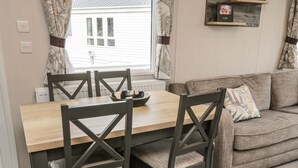 A dining area with a wooden table and four chairs, a sofa, and a wall-mounted shelf with a picture and the word "LOVE". - Kelly's Retreat (Scarborough)