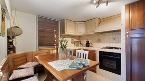 A kitchen with wooden cabinets, a dining table with benches, a stove, and an oven. - Lemon Green Apartment (Celle Ligure)