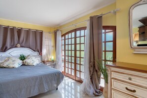 A bedroom with a bed, curtains, a dresser, and a window with a view. - Lemon Green Apartment (Celle Ligure)
