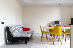 Een moderne woonruimte met een bank, gele stoelen, een eettafel en een magnetron.