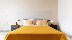 A neatly made bed with a yellow bedspread, two bedside lamps, and a nightstand with a lamp. - Apartment 'Civico 23 Matera' with Balcony, Wi-Fi and Air Conditioning (Matera)