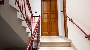 A staircase with red railings leading to a wooden door. - Apartment 'Civico 23 Matera' with Balcony, Wi-Fi and Air Conditioning (Matera)