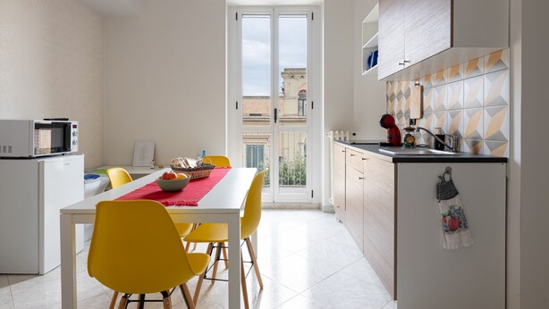A compact kitchen with a dining area, a microwave, and a view through a glass door. - Apartment 'Civico 23 Matera' with Balcony, Wi-Fi and Air Conditioning (Matera)