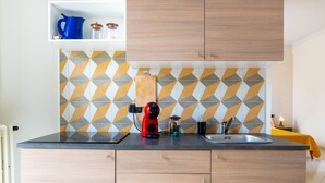 A modern kitchen with a geometric tile backsplash, a coffee machine, and a sink. - Apartment 'Civico 23 Matera' with Balcony, Wi-Fi and Air Conditioning (Matera)